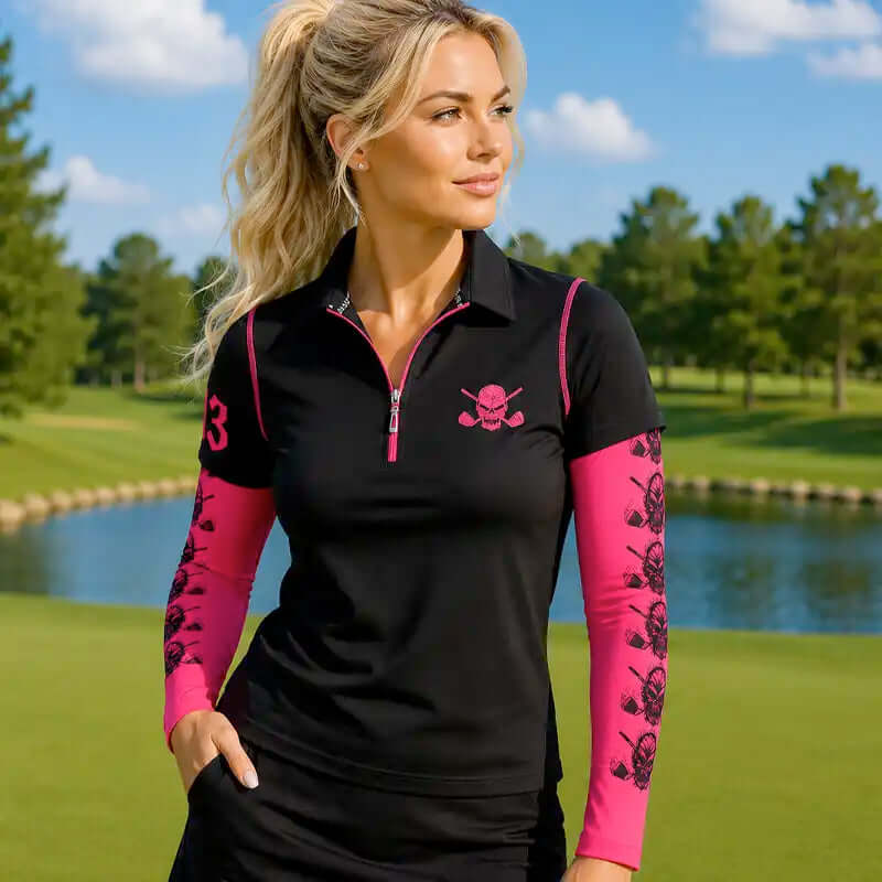 Woman wearing a black and pink golf shirt with a skull and crossbones design on a golf course.
