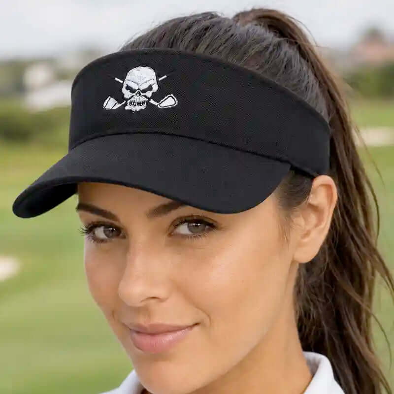 A woman wearing a black golf visor with a white embroidered skull and crossed golf clubs logo,