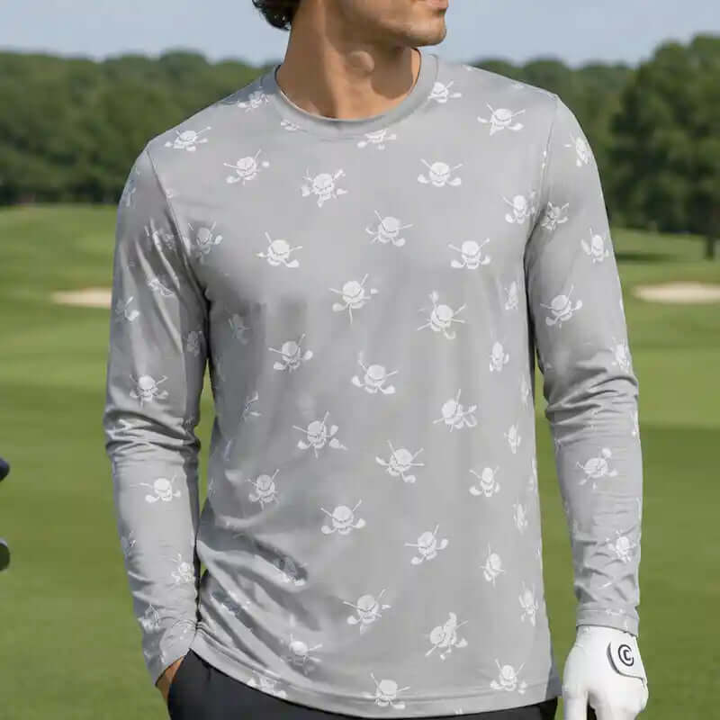 golfer wearing a gray long-sleeve shirt with skull and crossbones pattern on a golf course.