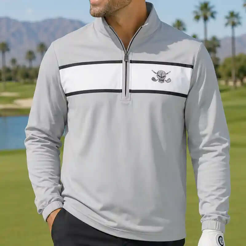 golfer wearing a gray golf pullover with a skull logo on a golf course