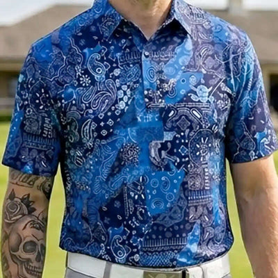 Person wearing a blue patterned shirt with tattoos visible on arms