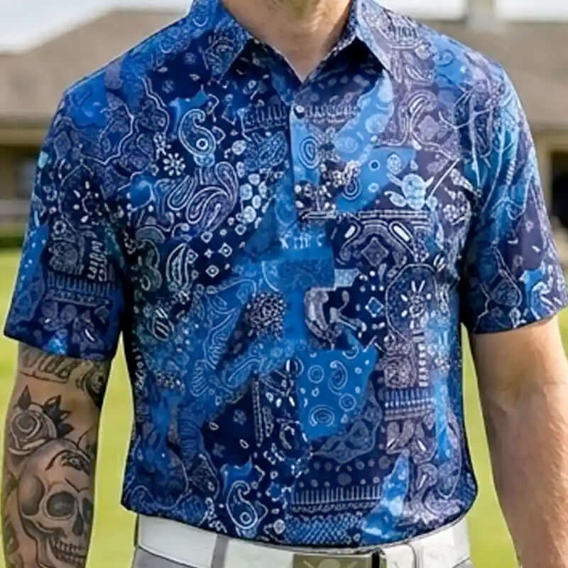 Person wearing a blue patterned shirt with tattoos visible on arms
