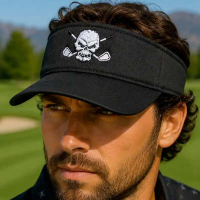 A man wearing a black golf visor hat with a white embroidered skull and crossed golf clubs logo on the front