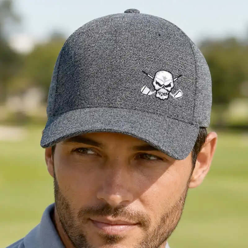 A man wearing a dark gray heathered golf hat with a white embroidered skull and crossed golf clubs logo on the front,