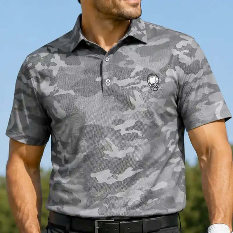 Man wearing a gray camouflage golf polo shirt with a skull logo against a blue sky.