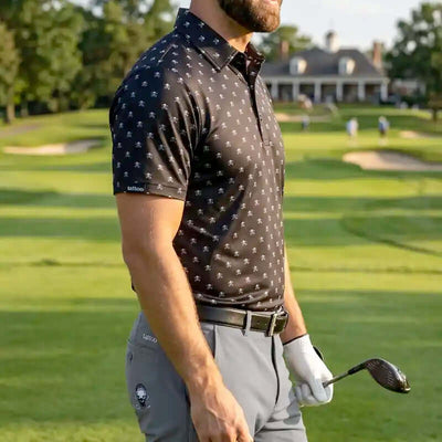 golfer on a golf course wearing a skull patterned shirt and golf pants holding a golf club.