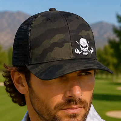 A man wearing a black camouflage trucker golf hat with a white skull and crossed golf clubs embroidered on the front