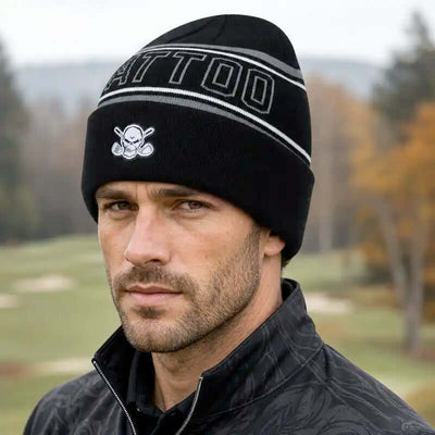 A man wearing a black knit beanie with white and gray stripes and a skull-and-crossbones logo