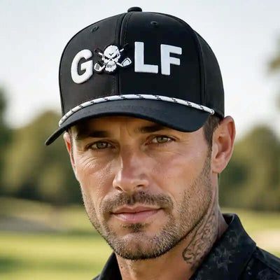 A man wearing a black golf hat with 'GOLF' and a skull-and-golf club graphic on the front, photographed outdoors with a blurred golf course background.