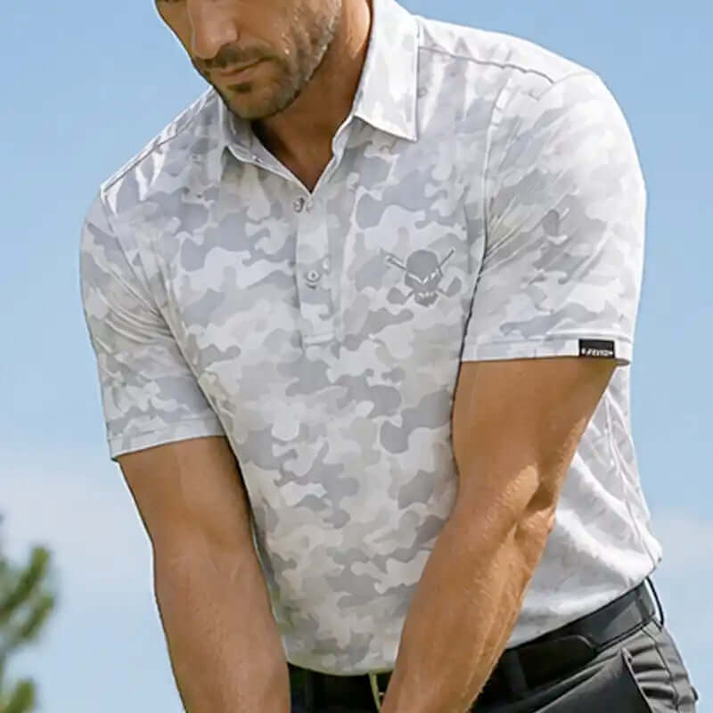 Man wearing a white camouflage-patterned polo shirt with a brand logo against a clear blue sky.