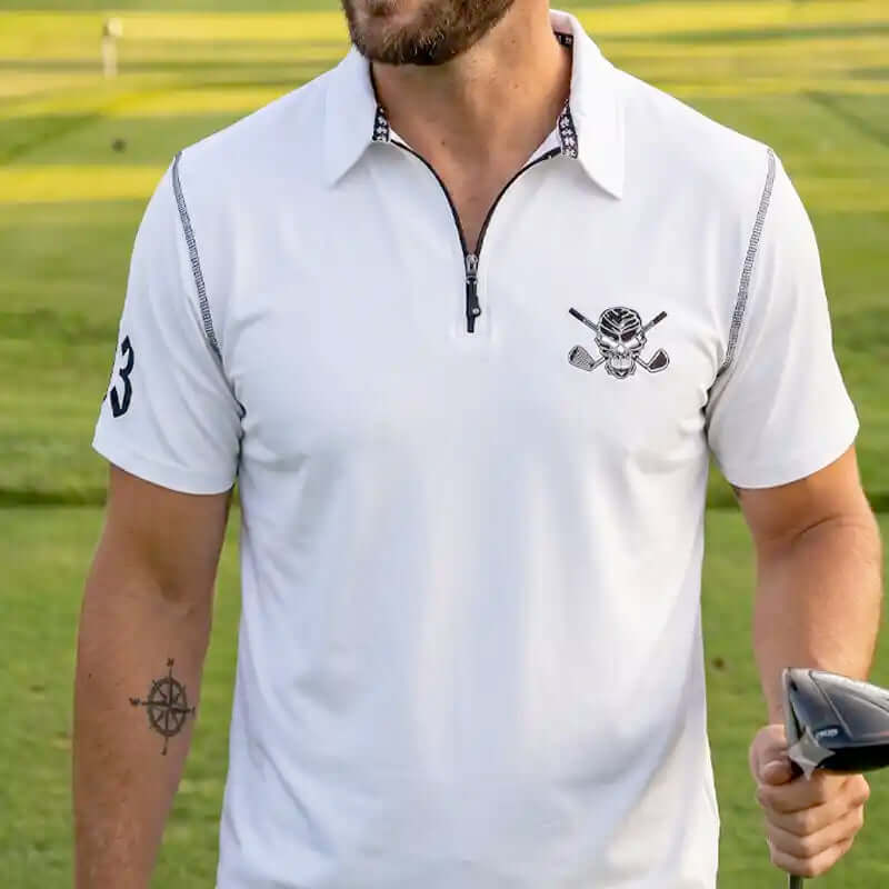 Man wearing a white polo shirt with a skull logo on a golf course