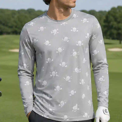 golfer wearing a gray long-sleeve shirt with skull and crossbones pattern on a golf course.