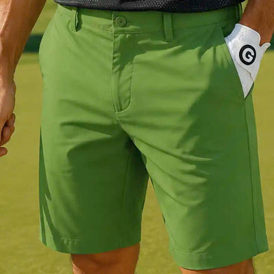 men's Green golf shorts worn by a person on a golf course with a golf glove in the pocket.