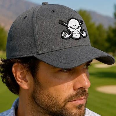 A golfer wearing a dark gray golf cap with a white and black skull and crossed golf clubs patch on the front