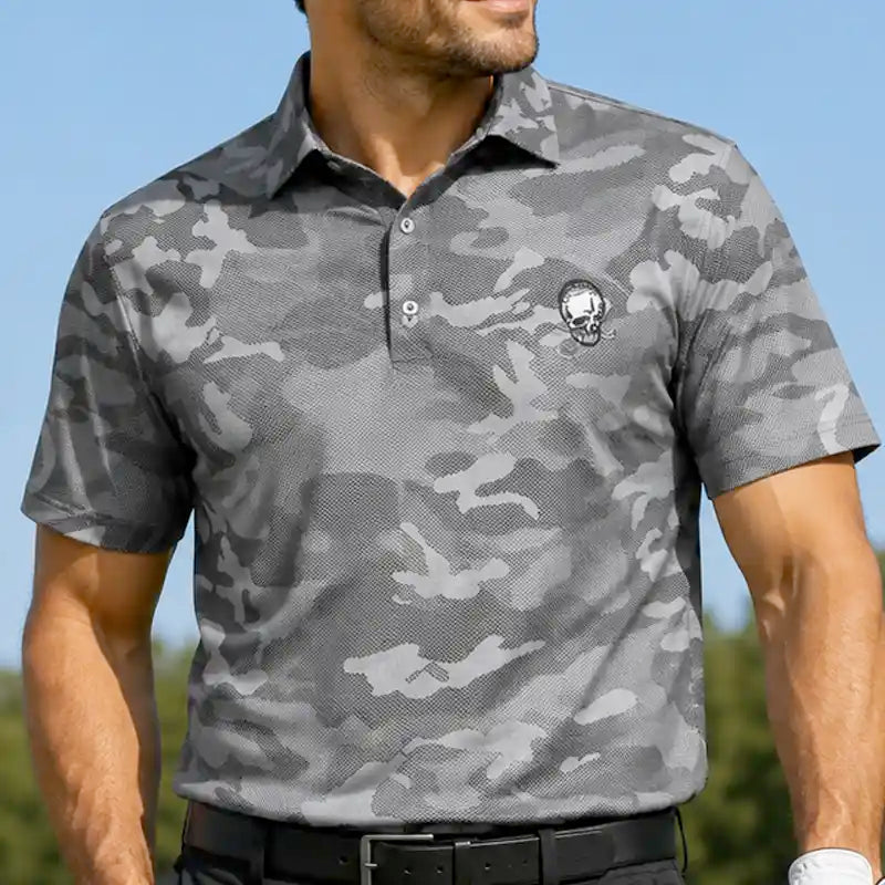 Man wearing a gray camouflage golf polo shirt with a skull logo against a blue sky.