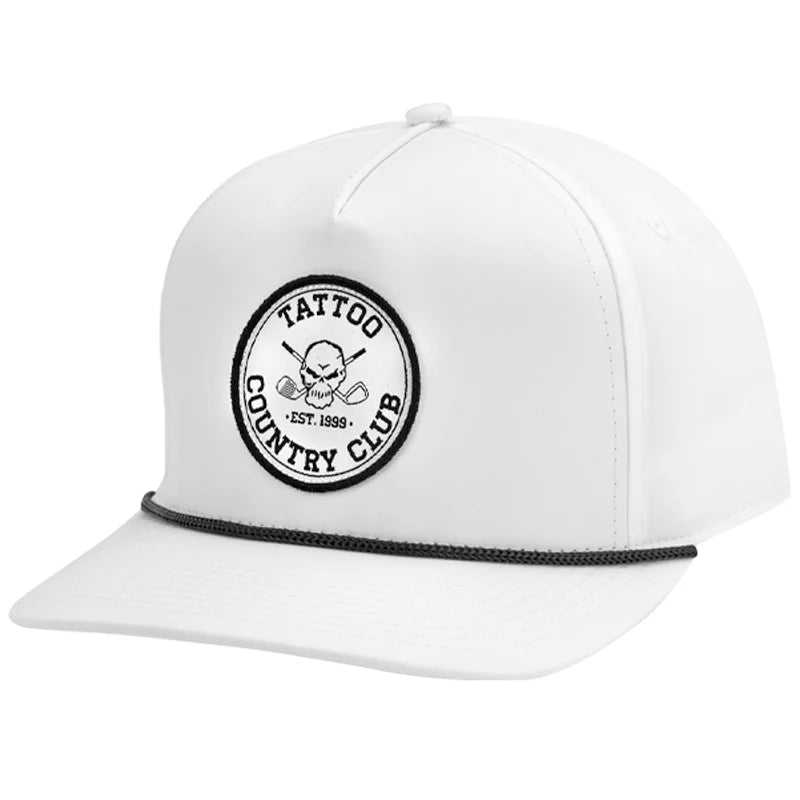 A white golf hat with a circular patch on the front featuring the Tattoo Country Club logo and a skull and crossing clubs design.