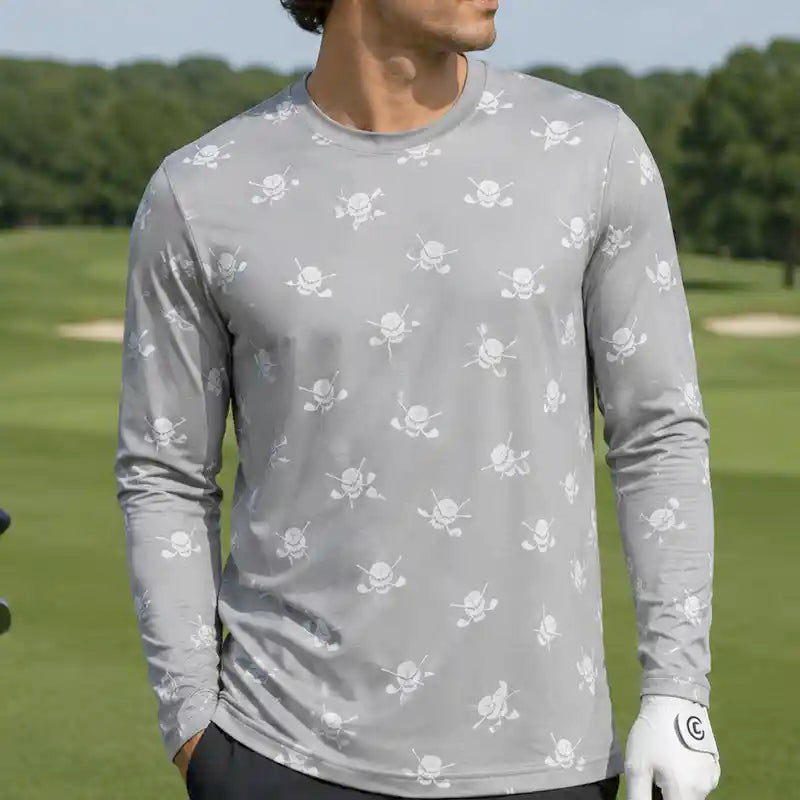golfer wearing a gray long-sleeve shirt with skull and crossbones pattern on a golf course.