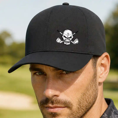 A man wearing a black baseball hat with a white embroidered skull and crossed golf clubs logo, set against a blurred golf course background.
