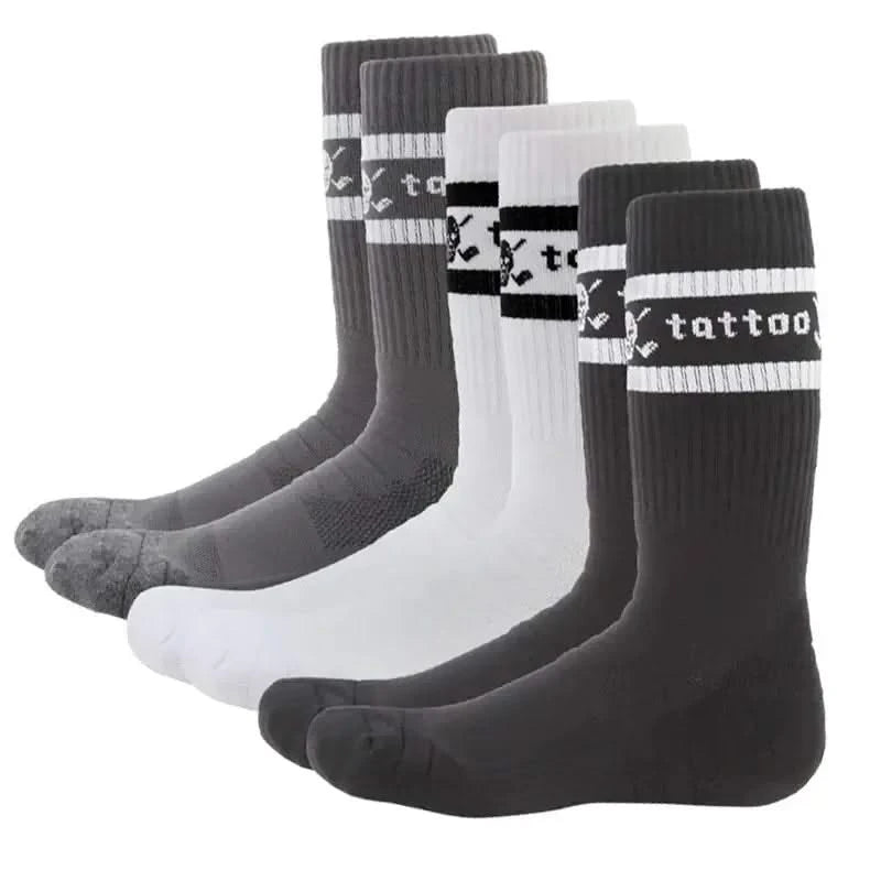 Three pairs of crew-cut golf socks, two in black and one in white, all featuring a skull and crossed clubs logo on the instep and the word 'tattoo' on the back. 