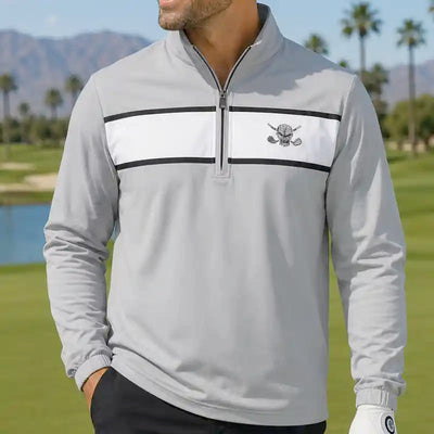 golfer wearing a gray golf pullover with a skull logo on a golf course