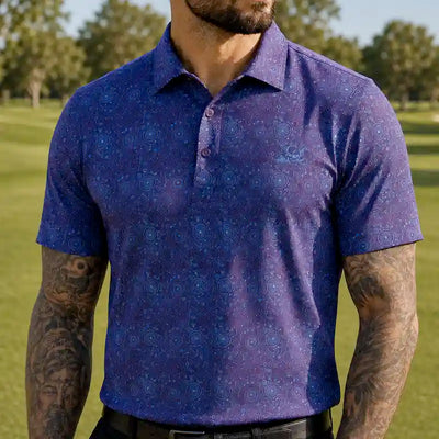 A golfer wearing a short-sleeve golf polo shirt with a blue and purple circular mandala pattern, photographed outdoors on a golf course.