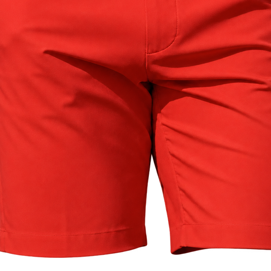 Close-up of the lower front of red golf shorts, showing the fabric folds and stitched hems.