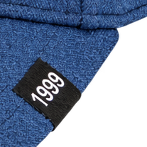 Close-up of a black 1999 label on a blue cap brim.
