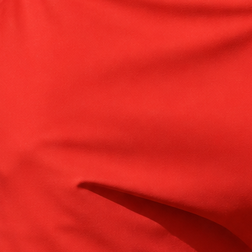 Close-up of red fabric showing a fold and part of a stitched seam.
