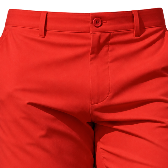 Close-up of red golf shorts showing the waist button, belt loops and front fly.