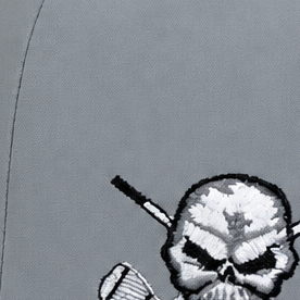 Close-up of the embroidered skull logo on a grey cap.