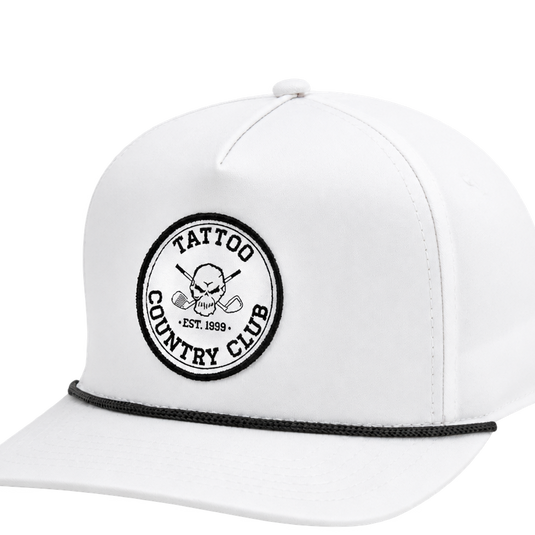 Close-up of a white cap's Tattoo Country Club patch and black rope trim.