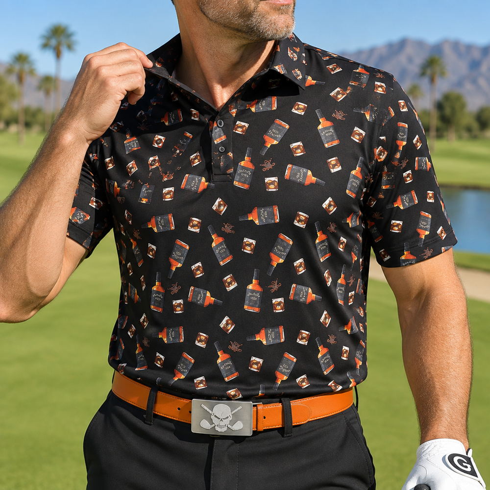Close-up of a golfer wearing a black whiskey-print polo and an orange skull-buckle belt on a golf course.