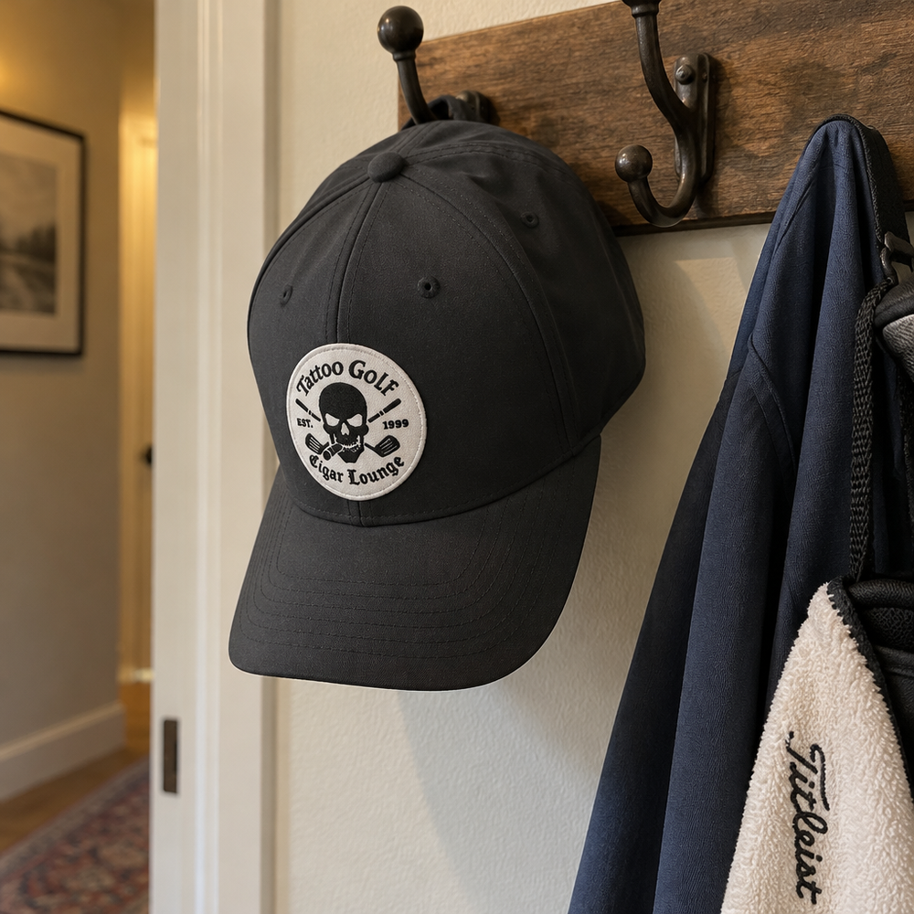Black Cigar Lounge cap hanging from a wall hook.