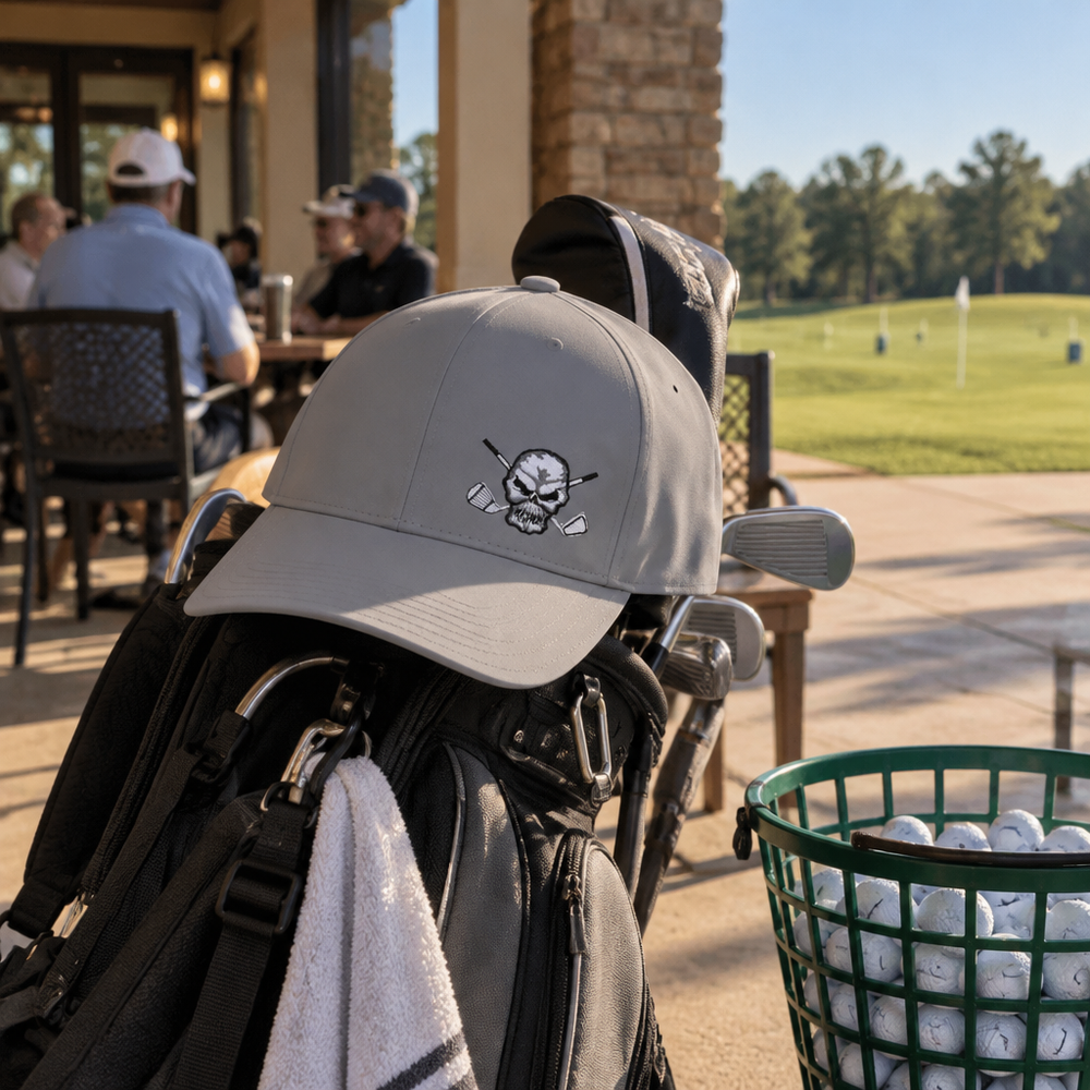 Grey skull-logo cap resting on a golf bag beside a clubhouse patio.