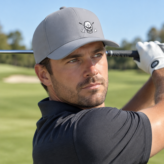Golfer finishing a swing in a grey skull-logo cap.