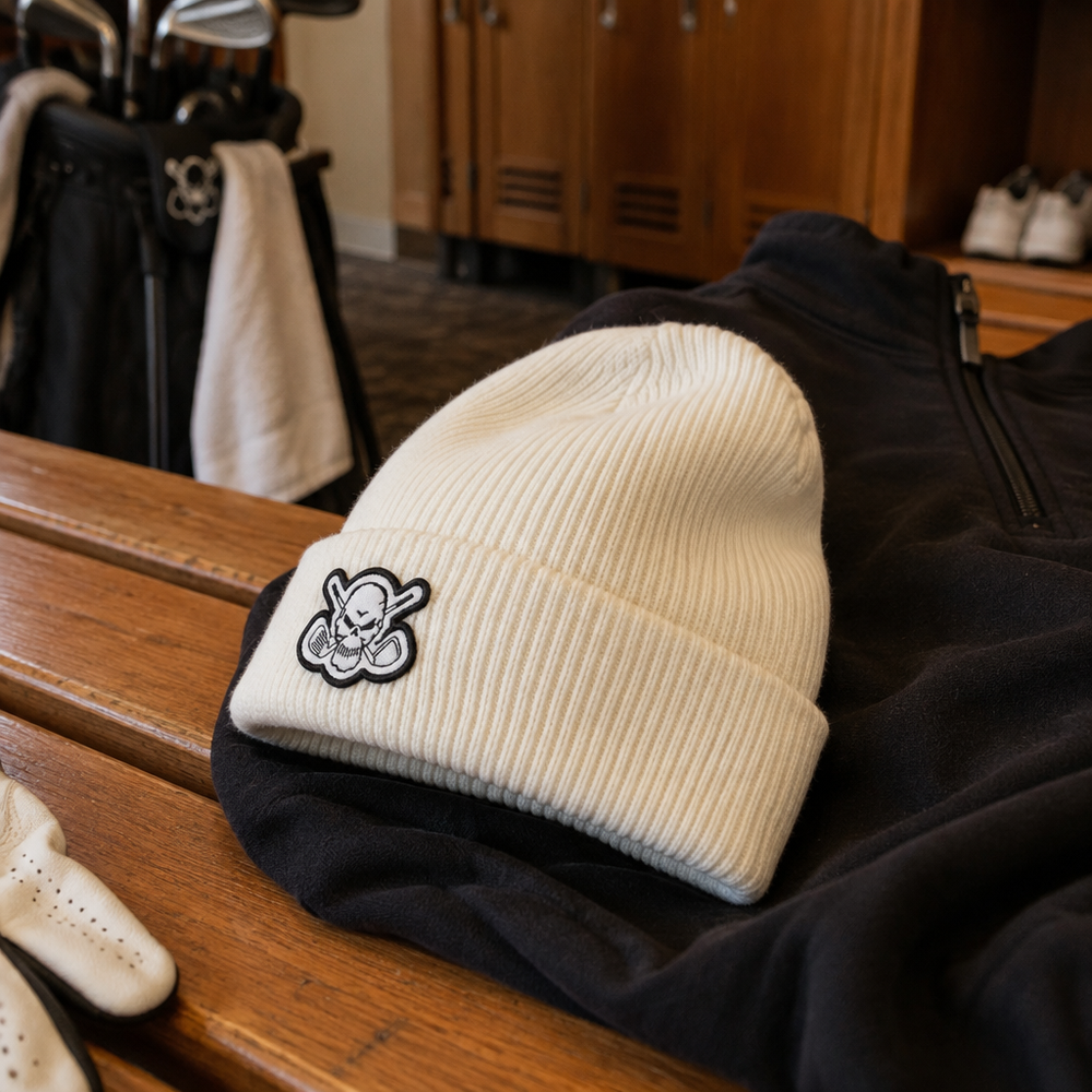 White skull-patch beanie resting on dark clothing in a locker room.