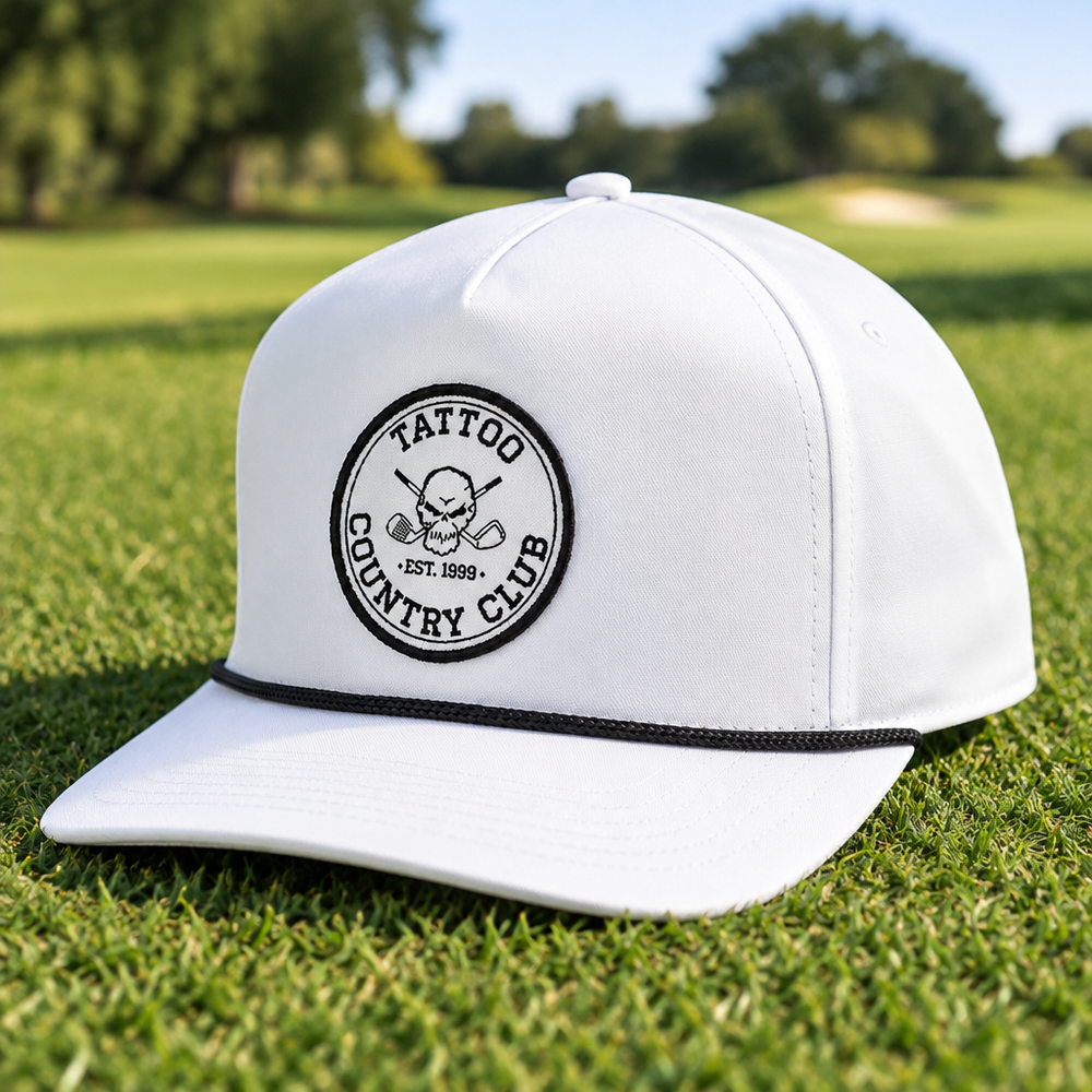 Angled view of a white Tattoo Country Club cap on a golf course.