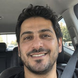 Portrait of a smiling dark-haired man seated in a car.