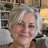 Portrait of a smiling grey-haired woman with glasses resting on her head.